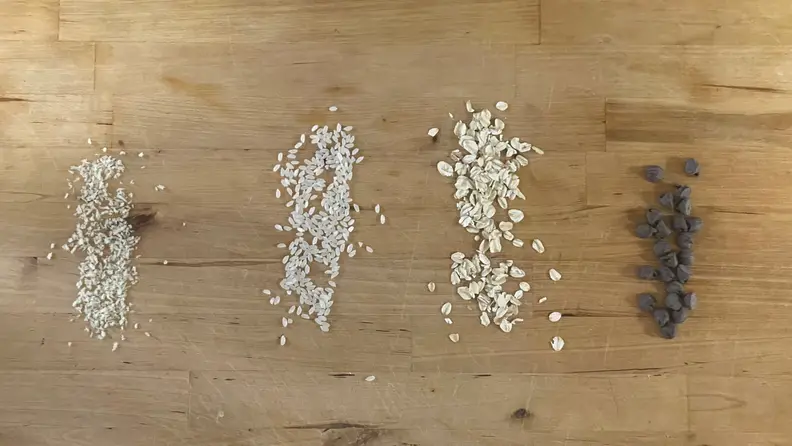 Piles of grits, rice, oats and chocolate chips on countertop.
