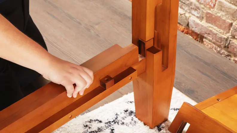 A person assembling the bed frame.