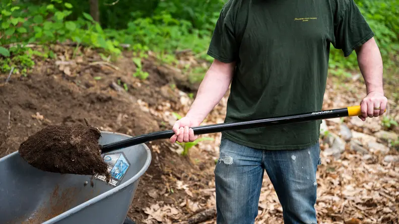 A person scooping dirt with the Fiskars Digging Shovel