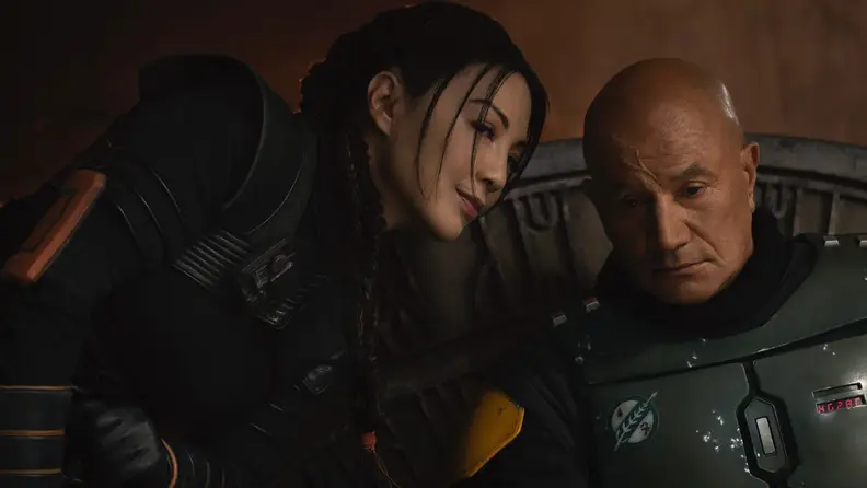 Two people huddled together while one smiles.