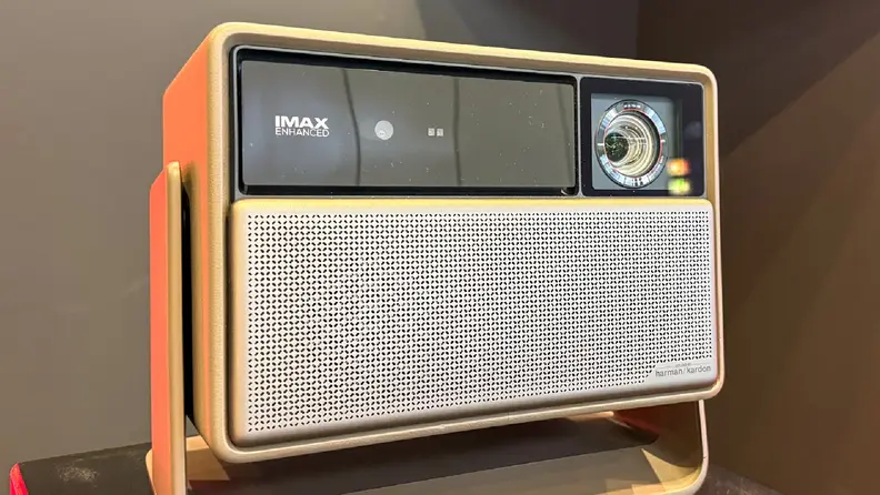 An XGIMI Horizon 20 series projector is displayed on a stand under bright lighting. The front panel shows the IMAX Enhanced logo alongside the lens, with a silver perforated speaker grille.