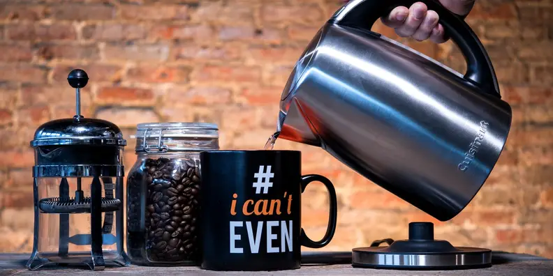 Person pouring hot water from tea kettle into mug.