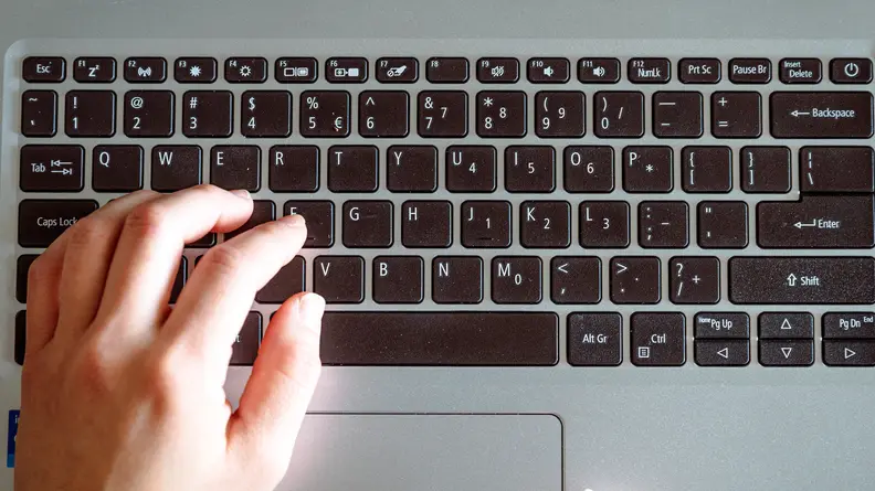 Person types on laptop keyboard