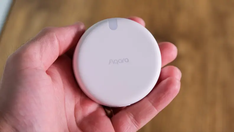 A hand holding the Aqara FP2 presence sensor.