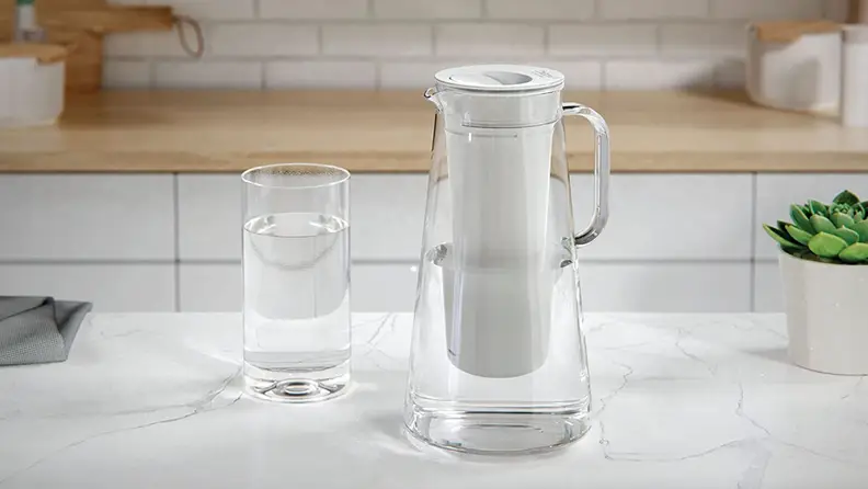 A Lifestraw pitcher and glass, both filled with water on a kitchen counter