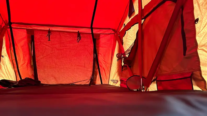 The red-hued interior of the Rugged Ridge Roof Top Tent with a flap closed and the mattress in the foreground.