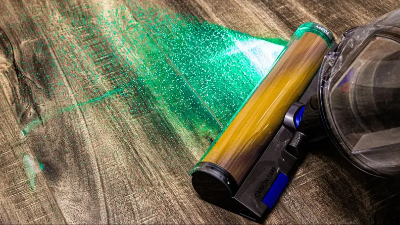 The Dyson Gen5outsize vacuum with a green light illuminated on the front as it vacuums up debris from a wood floor