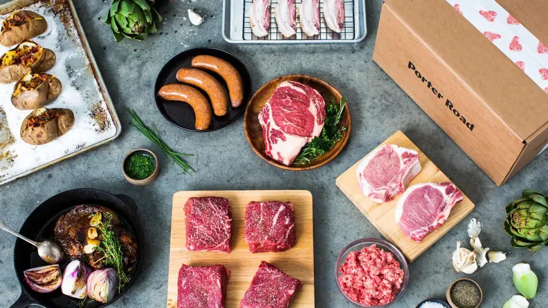 Several raw cuts of meat and a Porter Road box laid out on a countertop