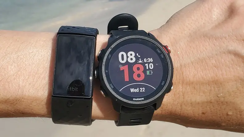 Fitbit Charge 4 and Garmin Forerunner 245 on a wrist