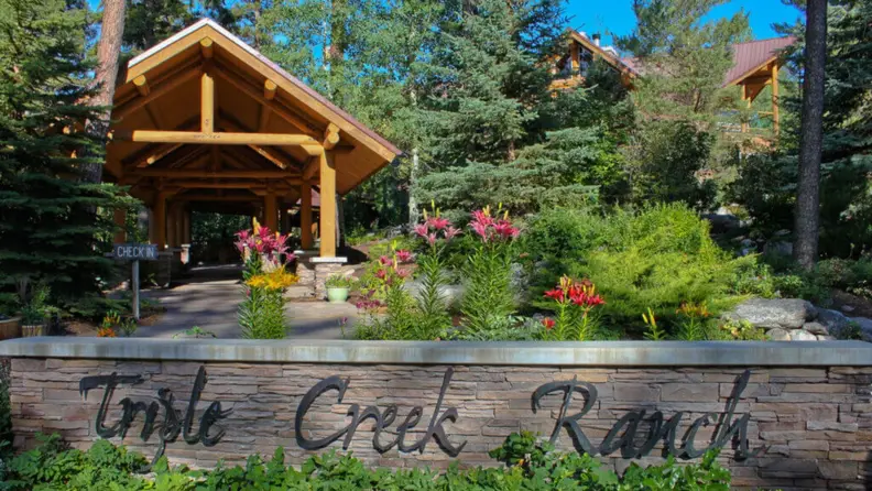 The entry to a ranch resort with lush greens and colorful flowers