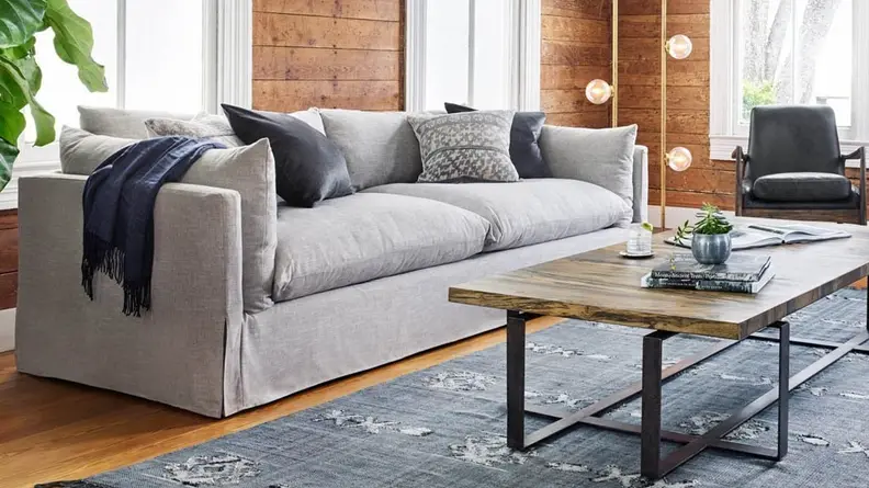 A grey, fluffy couch sits in a modern living room in front of a coffee table.