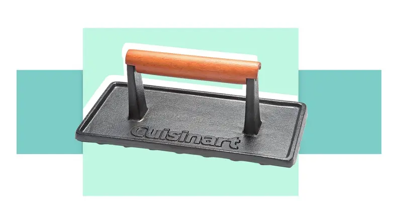 A cast-iron grill press in front of a background.