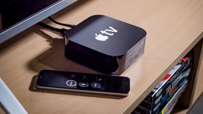 An Apple TV device and remote sit underneath a television.
