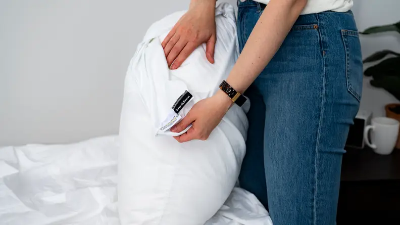 a woman pulls the Brooklinen pillow protector off a pillow