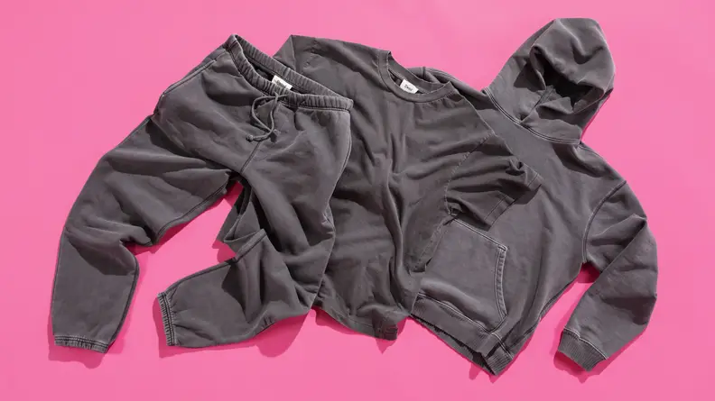 The Elwood Core Tee, Sweatpant, and Hoodie laid out on a pink background.