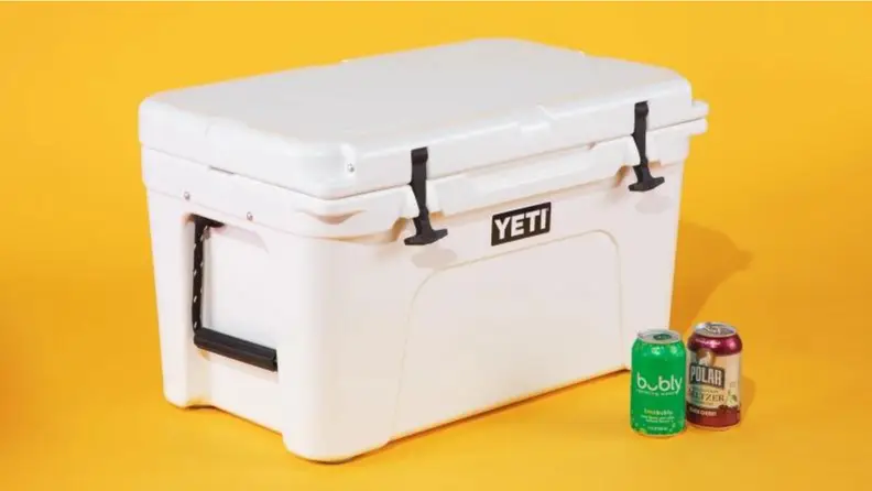 White yeti tundra 45 cooler sits on a yellow background with two cans of seltzer in front of it