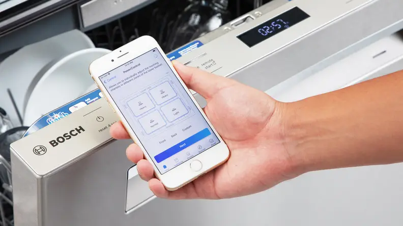 A person holding a smart phone next to the Bosch SHP78CM5N 800 Series in the color silver.
