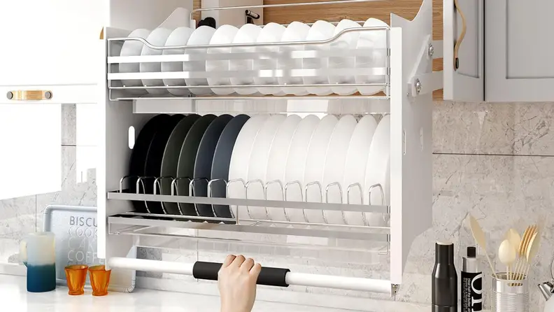 A hand pulls down on the handle of a Whifea pull-out cabinet organizer. Plates sit in the organizer.