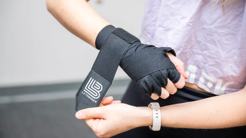 A woman wrapping her hands with the Liteboxer hand wraps.