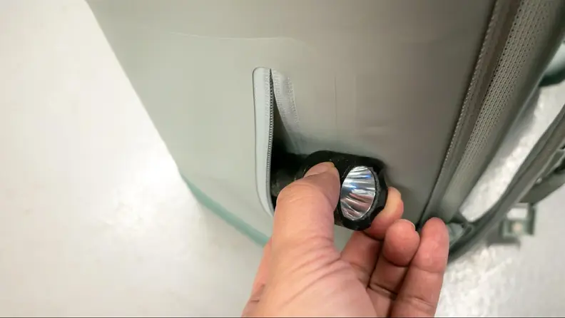 A flash being placed into a side pocket of the Brümate Magpack.