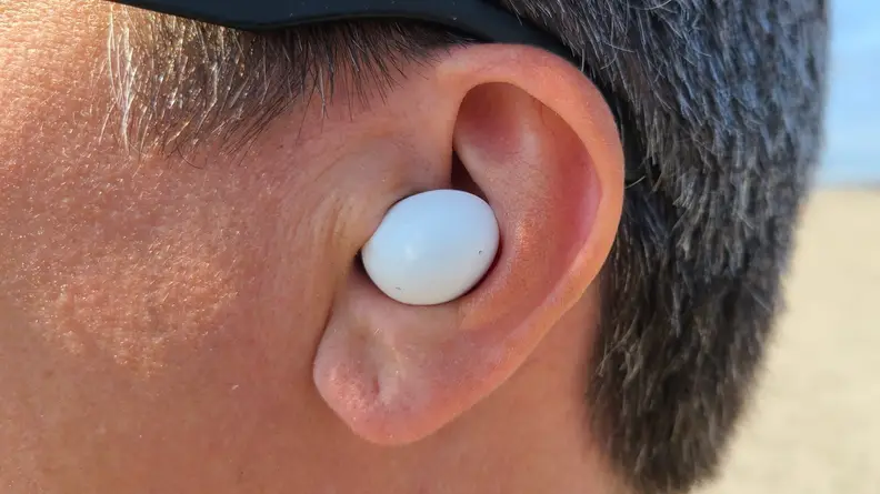 Samsung Galaxy Buds 2 is shown in the ear against a sunny beach.