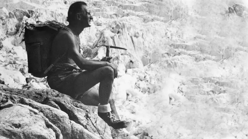 A black and white image of mountaineer and entrepreneur Vitale Bramani sitting on the edge of a cliff.
