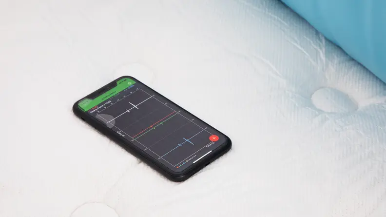 Smart phone sitting on surface of  the WinkBed hybrid mattress testing its pressure levels.