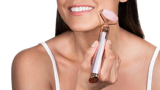 A person uses a vibrating facial roller