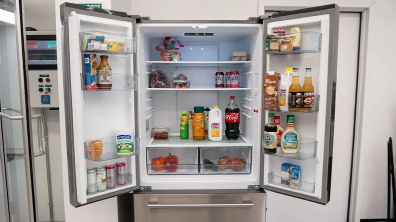 A close-up of the fridge with its top two doors open, revealing an interior stocked with food.