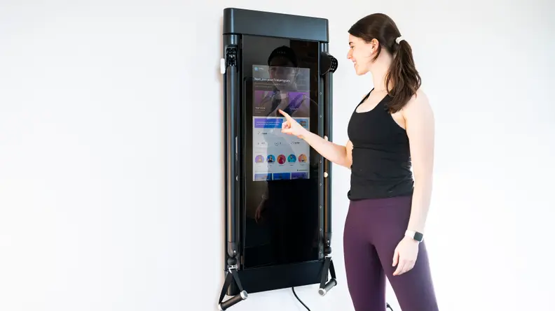 A woman selecting a workout on Tonal's touchscreen.