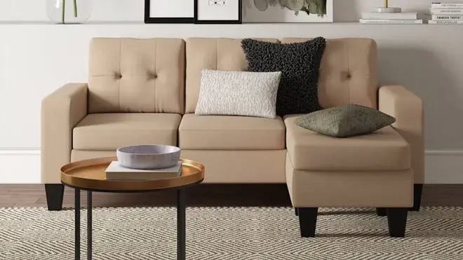 Nude couch against white wall on a patterned carpet