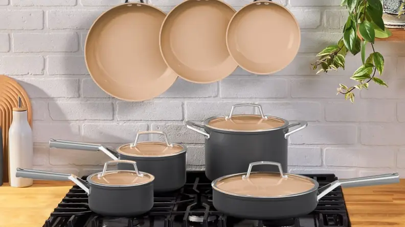 Assorted two-toned Ninja pots and pans on top of range in front of tile wall in kitchen.