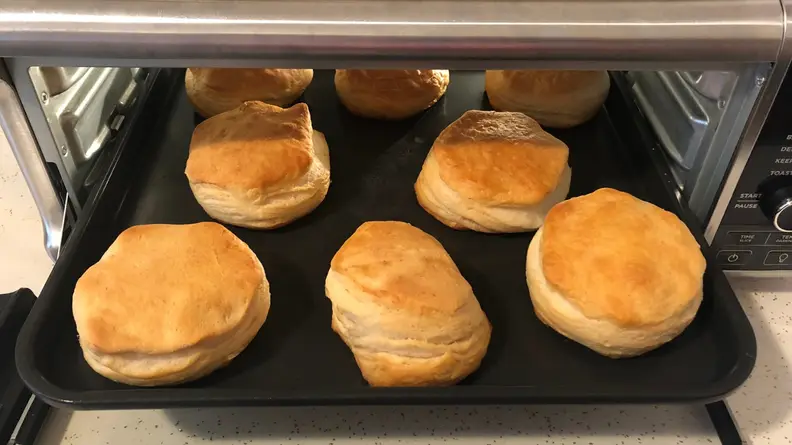 A tray of golden brown biscuits comes out of the Ninja Foodi Air Fryer Oven.