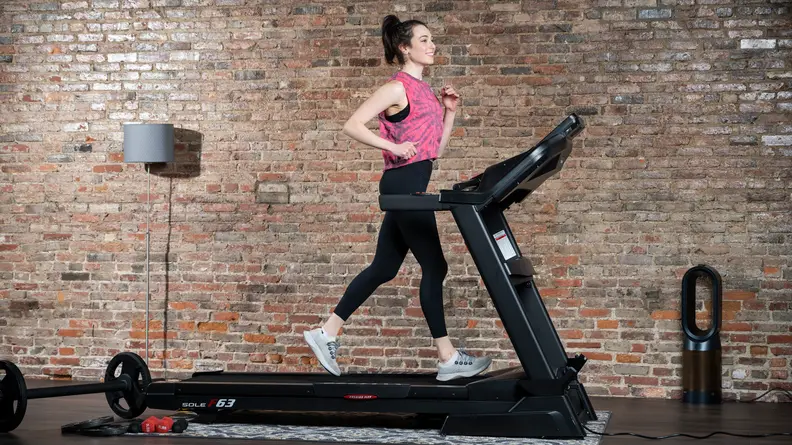 A woman uses the Sole F63 treadmill.