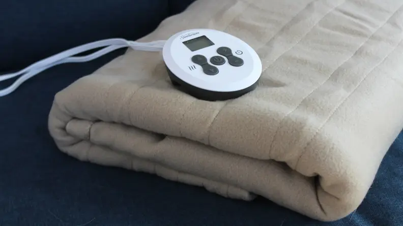 The Sunbeam Fleece electric blanket folded on a couch.