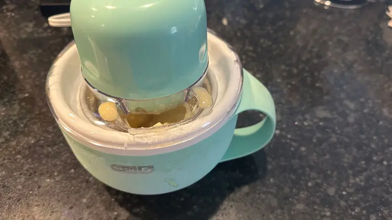 Dash My Mug Ice Cream maker churning mango sorbet on granite countertop.