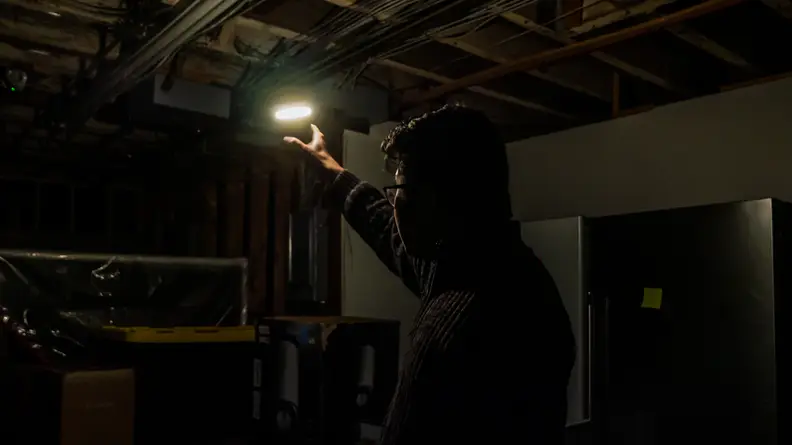 A man using the M150's ring light to illuminate a dark basement.