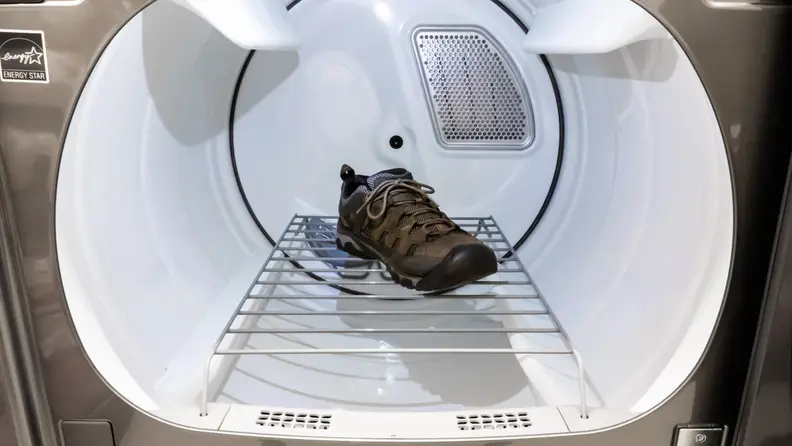A close-up of the Maytag MED8230HC dryer's drum with the shoe rack installed. A single sneaker lays suspended on the rack, which straddles the moving parts of the drum, allowing to shoe to sit still without tumbling.