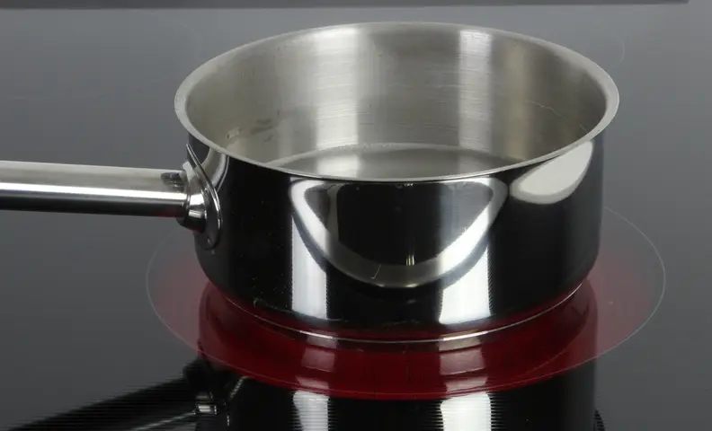 An electric cooktop with a sauce pan on it.