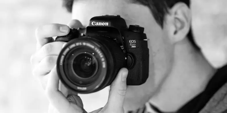 With a DSLR you want to support the camera's weight from underneath by grabbing the lens.