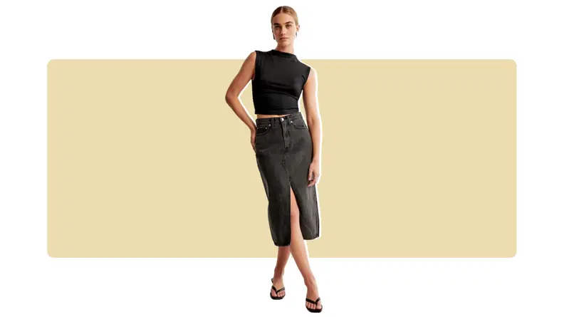 A model wearing a black midi-length denim skirt with a black tank top.