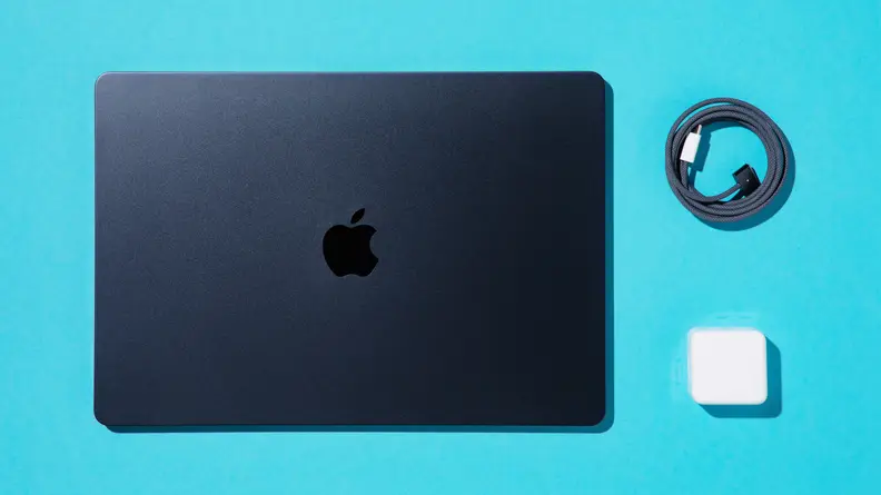 MacBook Air 15 M2 closed next to lightning cord and charger block.