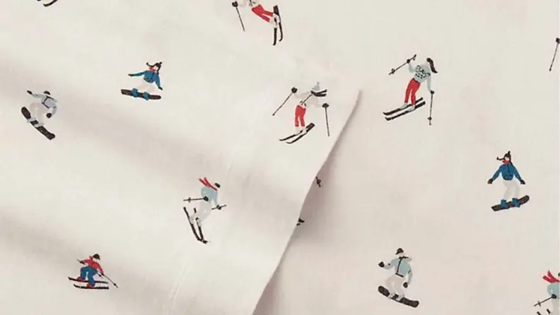 a close-up photo of Eddie Bauer flannel sheets with a cream background and skiers