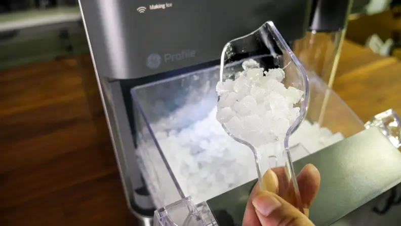Hand holding a scoop full of nugget ice over the GE Profile Opal 2.0