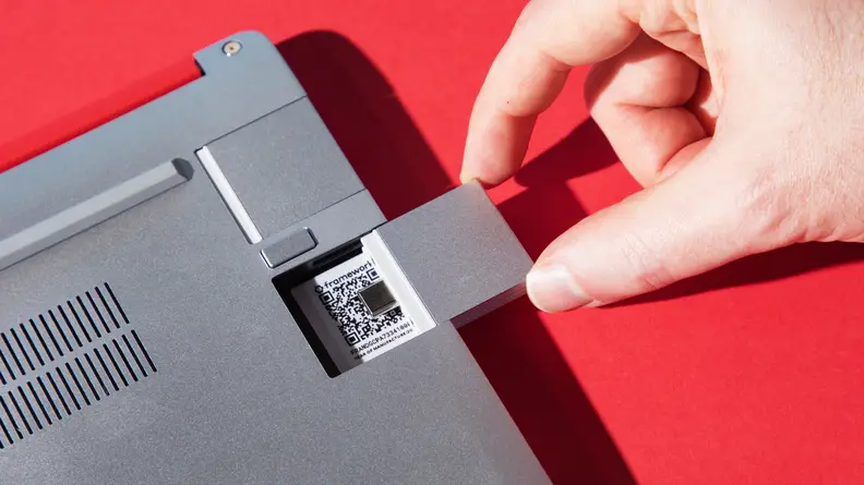 A hand switching out a port card for the laptop.