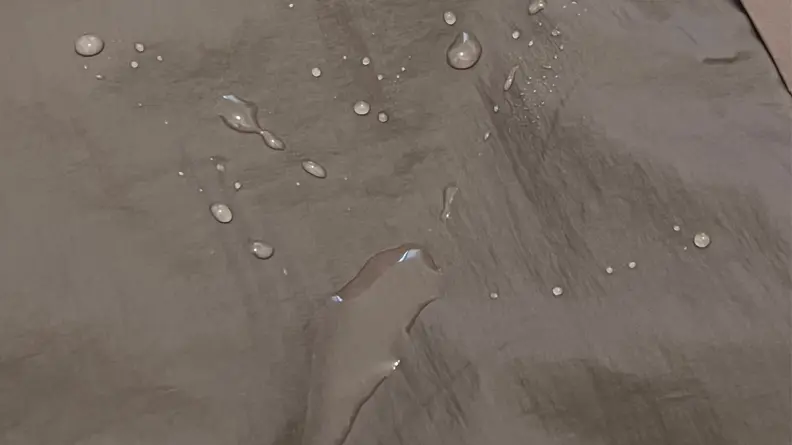 An image of a brown fabric with droplets of water scattered over it, not sinking into the fabric.