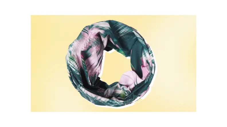 A pink and green floral-printed Buff head cover wrapped into a circle against a yellow background.