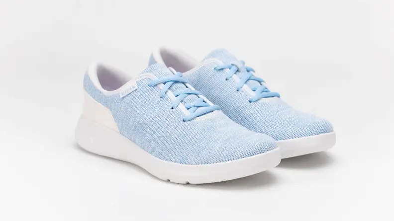 A pair of baby blue Kizik shoes against a gray background