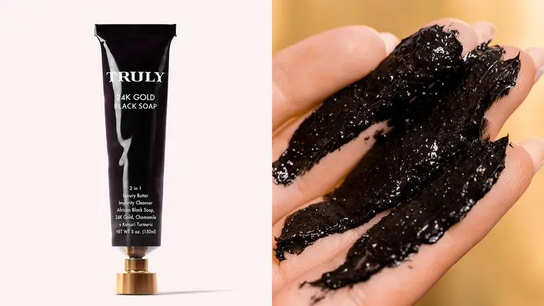On the left: The black tube of the Truly Beauty 24K Gold Black Soap Impurity Cleanser standing on a light pink background. On the right: A closeup of a hand with the black scrub on it.
