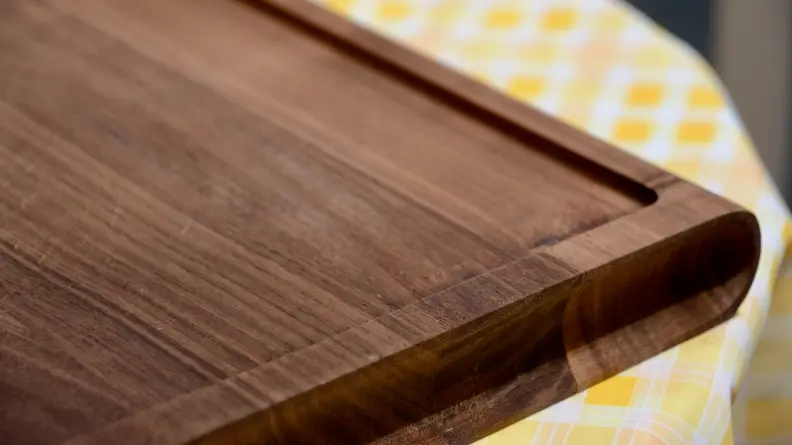 A close-up look at the Our Place walnut wood cutting board with a juice trench.